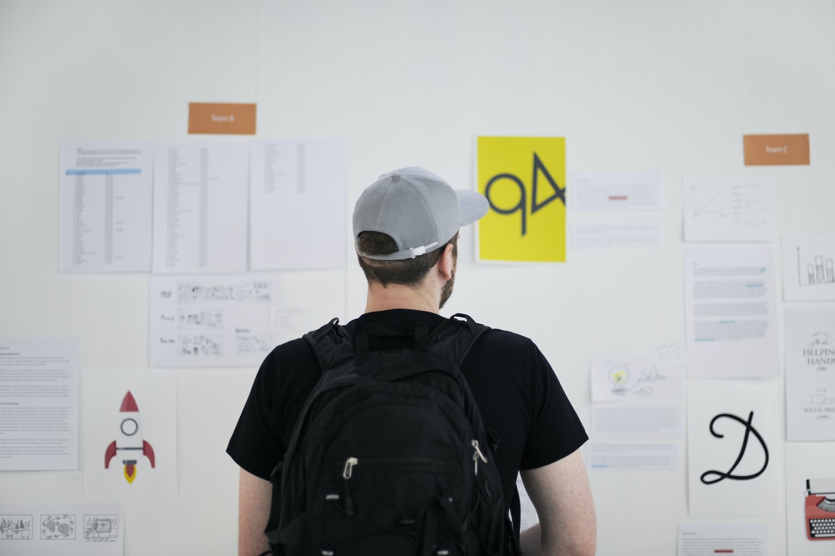 A man reviews designs and notes on the wall during part of the agile planning process.