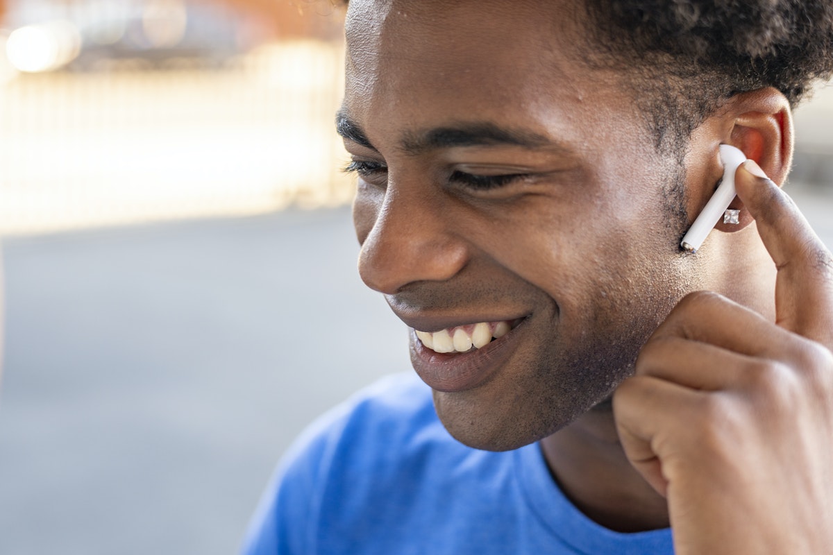 A man uses Airpods wireless headphones to take a call while outside.