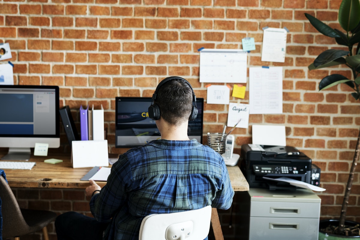 A man sits at a desk while working on a computer in an urban office space.