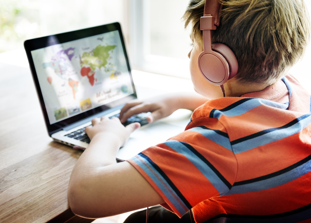 A student learns during an online geography lesson while wearing headphones, following distance learning best practices.