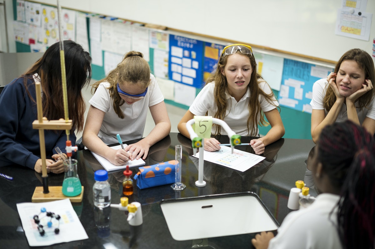 A group of students gather for an in-class science experiment as part of their hybrid learning classroom.