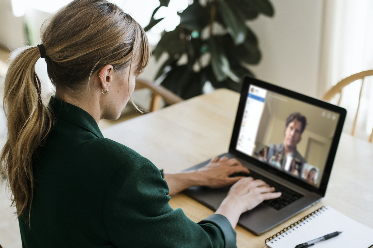 A woman sits in front of her laptop while participating in virtual meetings.