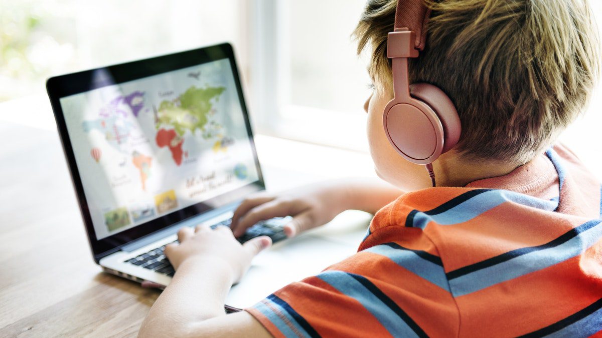 A student learns during an online geography lesson while wearing headphones, following distance learning best practices.