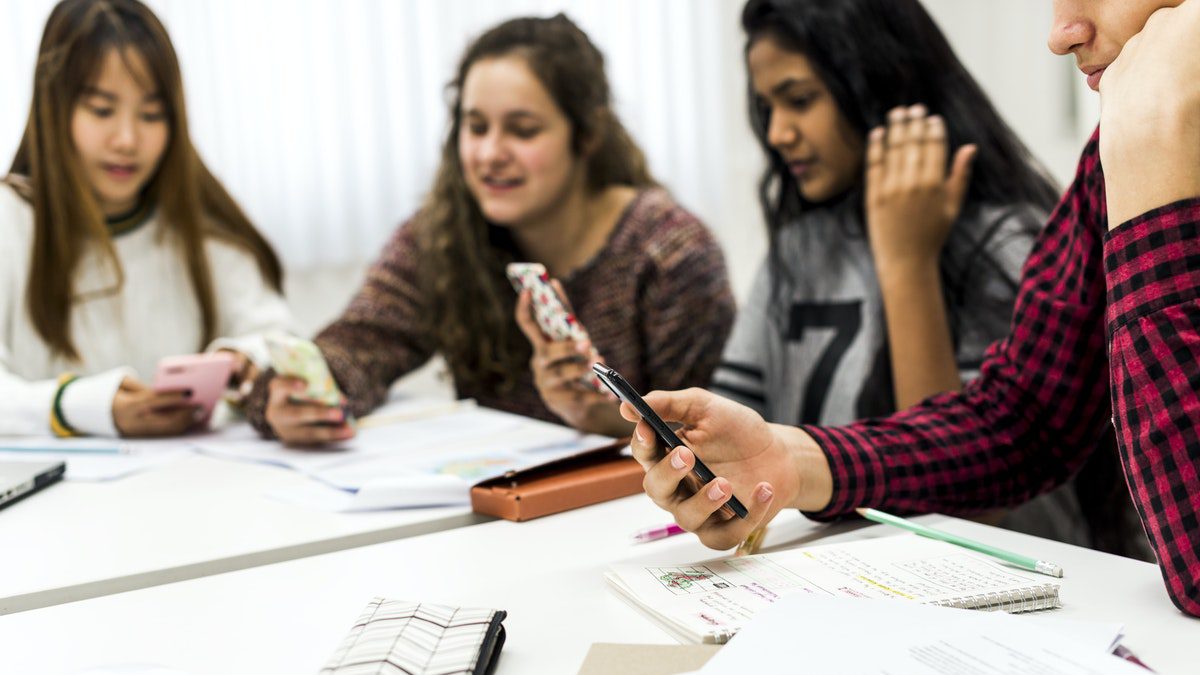 Students using smartphones in class to record and complete assignments.